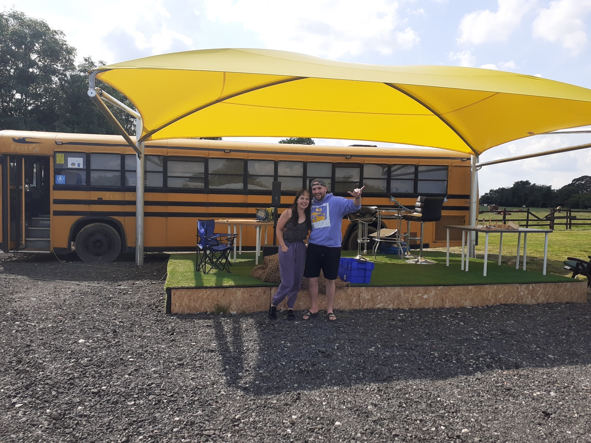 Chrissy and Mike stood in front of The Old Farm Bus - a yellow American-style school bus